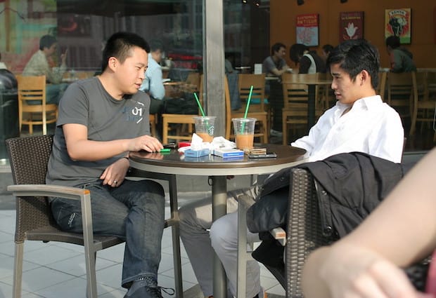 Chinese men at an outdoor table drinking Starbucks
